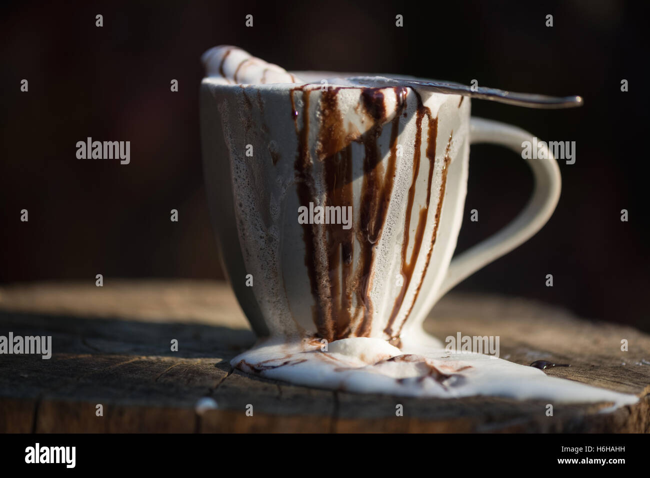 Sehr chaotisch heiße Schokolade mit Schlagsahne und Schokolade Sauce überlaufen einen Becher set auf Baumstumpf Stockfoto