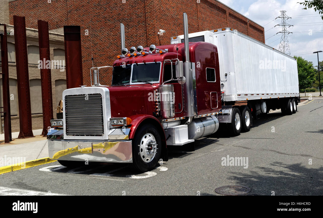 Rot halb Kabine mit weißen weißen Anhänger entlang Seite Backsteinbau geparkt. Stockfoto
