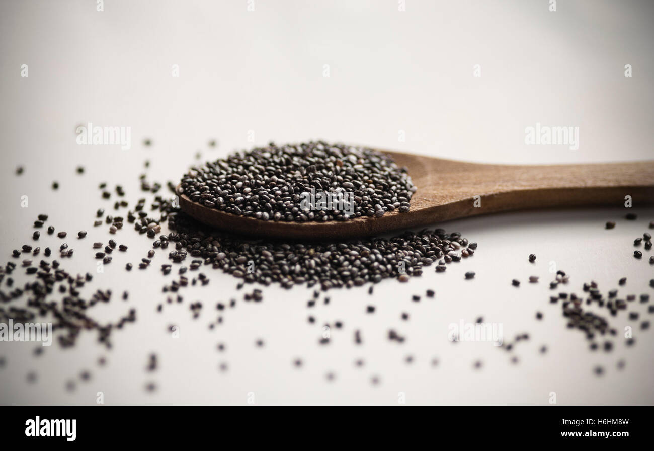 Chia-Samen in Holzlöffel erschossen als Makro auf weißem Hintergrund mit Vignettierung Stockfoto