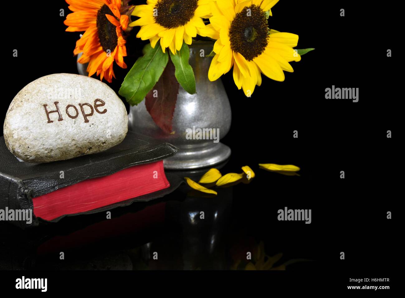 Wort Hoffnung gemeißelt in Stein auf Bibel mit Sonnenblumen Blumenstrauß in Zinn Krug Stockfoto