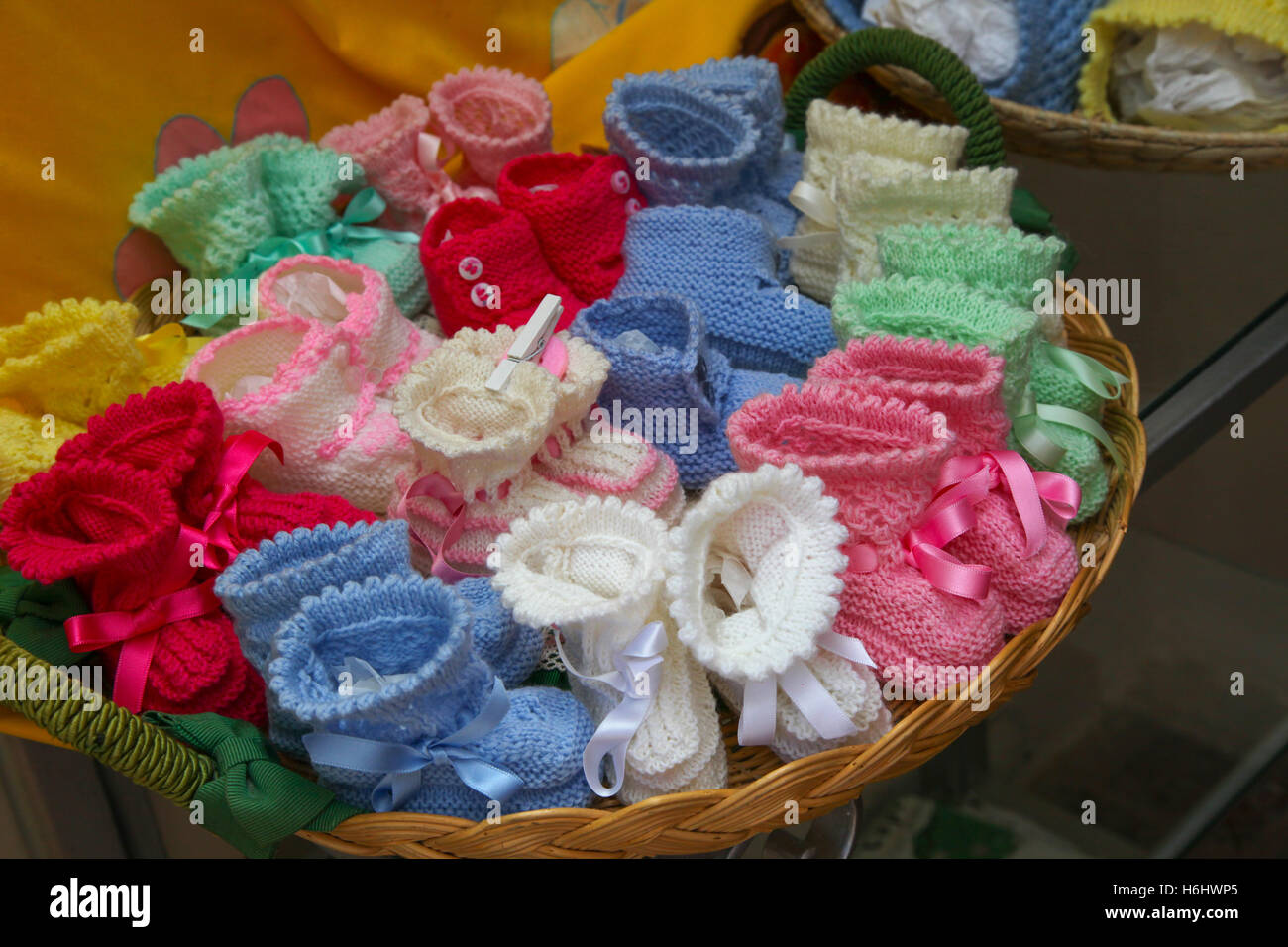 Weidenkorb voller Baby Bootie handgefertigt von einer alten Dame auf einer Seitenstraße in Sorrent Italien gemischte rosa blau Paare Peg gestrickt Stockfoto