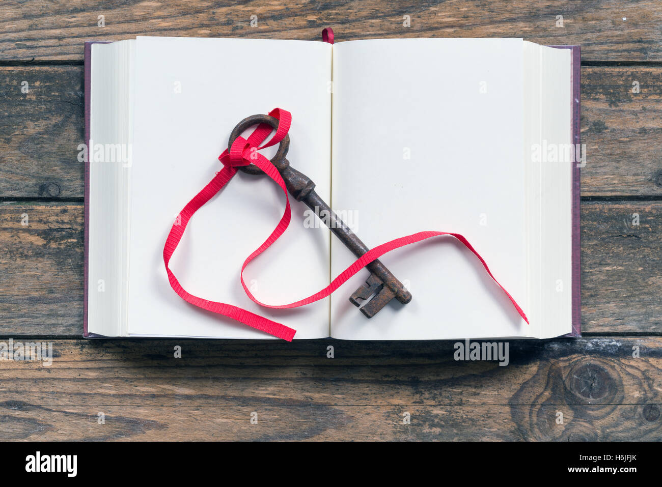 Schlüssel mit einem roten Band auf ein leeres Buch gebunden Stockfoto