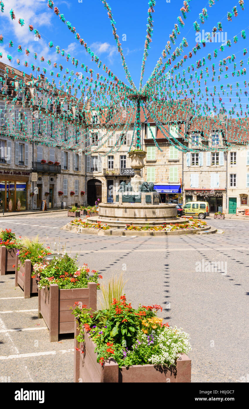 Springbrunnen und die umliegenden Gebäude in Place De La Liberté, geschmückt für eine Fête, Arbois, Jura, Frankreich Stockfoto
