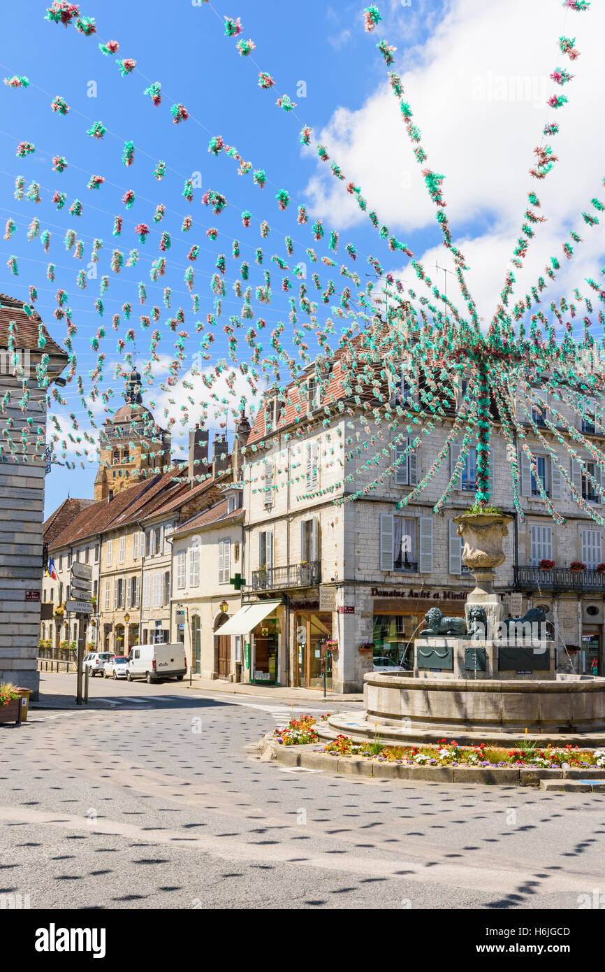 Springbrunnen und die umliegenden Gebäude in Place De La Liberté, geschmückt für eine Fête, Arbois, Jura, Frankreich Stockfoto
