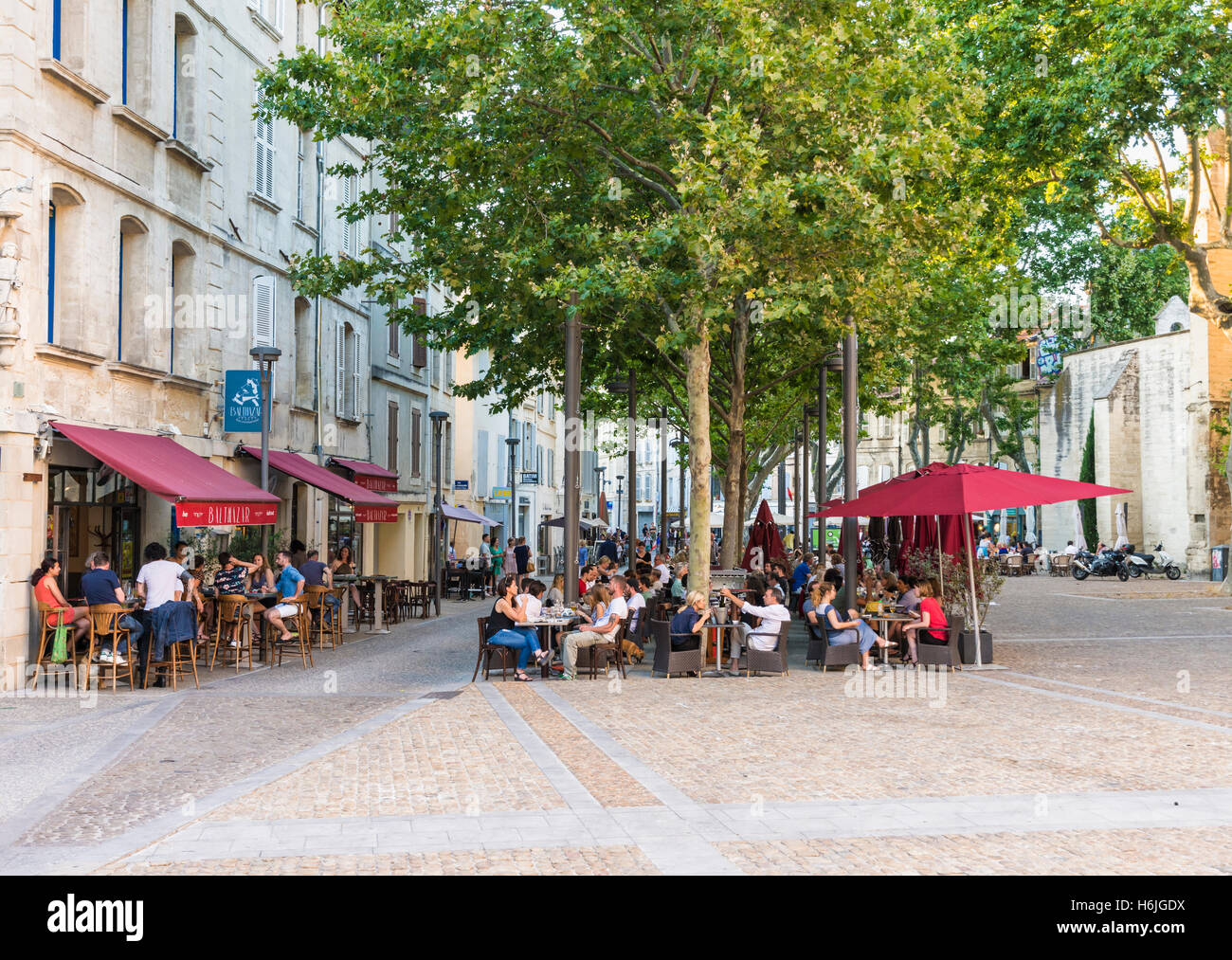 Menschen Essen im Restaurant im Freien Tische in den frühen Abendstunden am Place des Corps Saints, Avignon, Frankreich Stockfoto