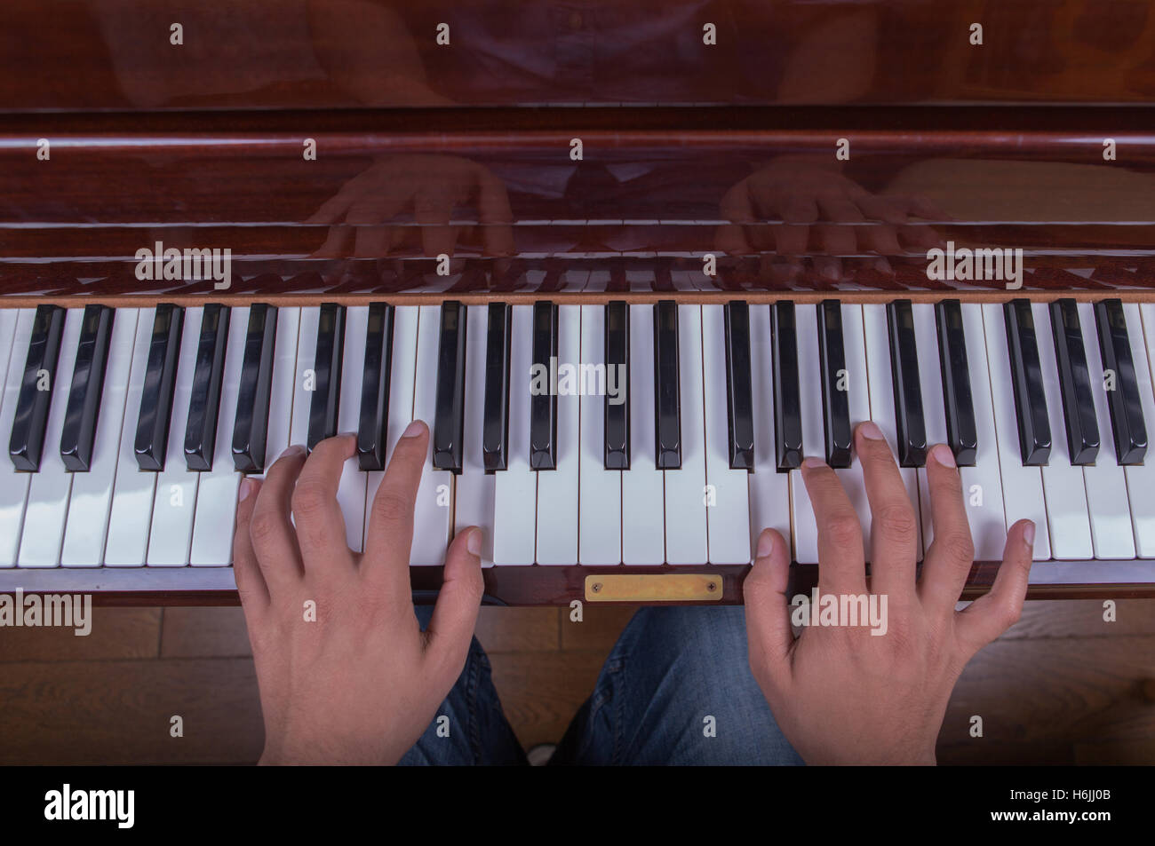 Mann in Blue Jeans mit beiden Händen Klavier spielen Stockfoto