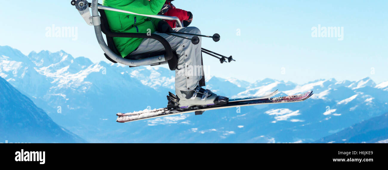 Skifahrer am Sessellift mit schneebedeckten Bergen im Hintergrund Stockfoto
