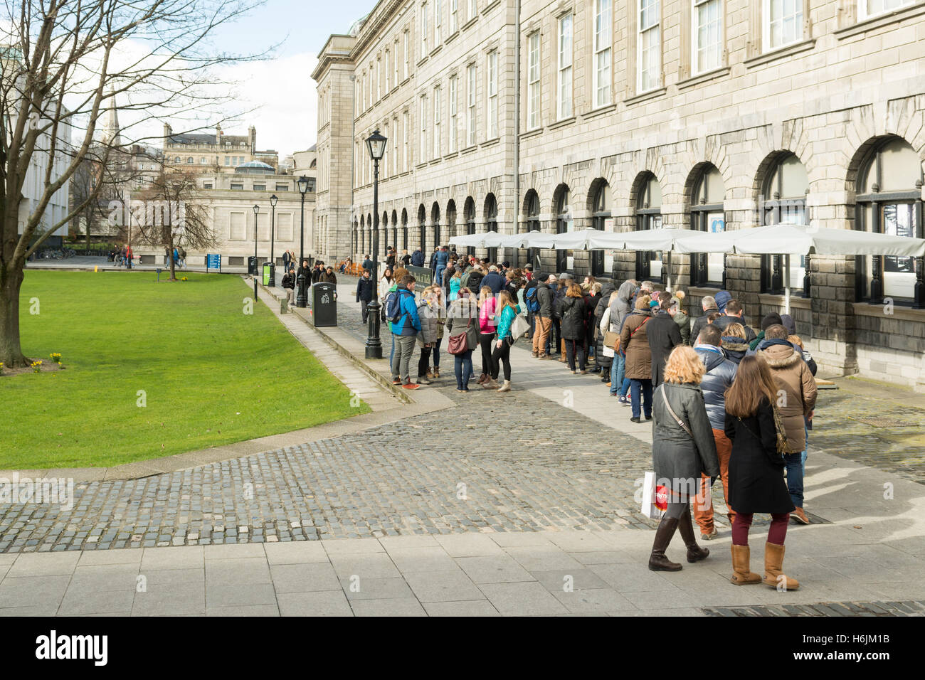 Buch von Kells Ausstellung Warteschlange - Menschen Schlangestehen vor der alten Bibliothek neben Fellows' Square, Trinity College, Dublin Irland Stockfoto