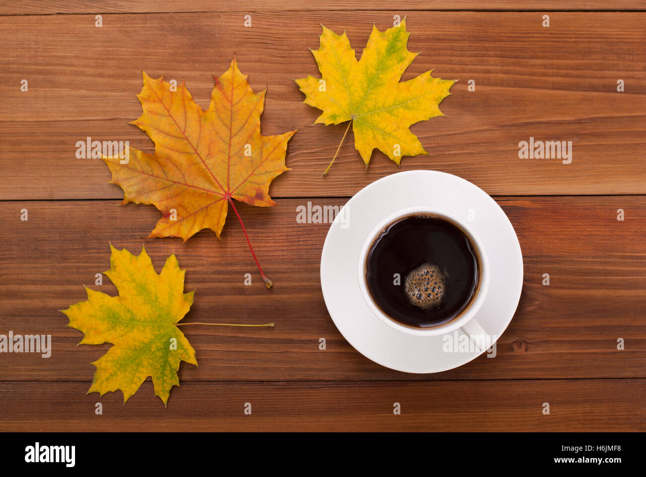 Tasse Kaffee und Ahorn Blätter auf einem Holztisch. Stockfoto