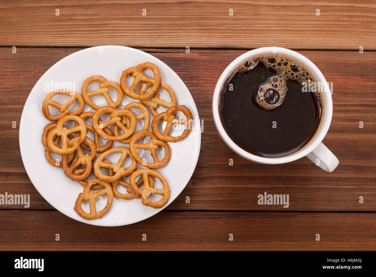 Tasse Kaffee und leckere Brezel auf einem hölzernen Hintergrund. Stockfoto