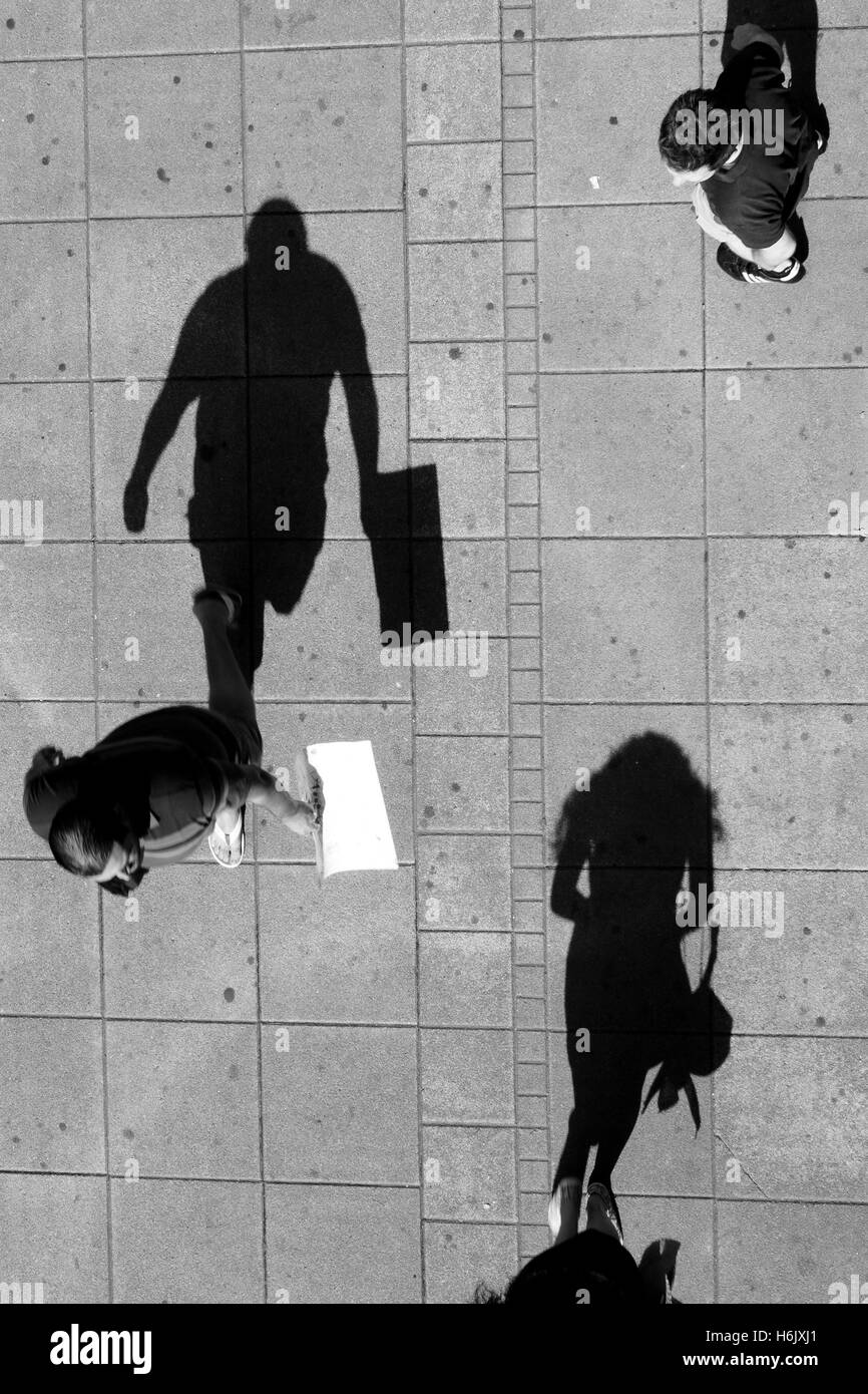 Wer ist dieses Mädchen - Schatten einer jungen Frau und zwei Männer auf der Suche nach ihr auf Stadt Bürgersteig im Sommer Stockfoto