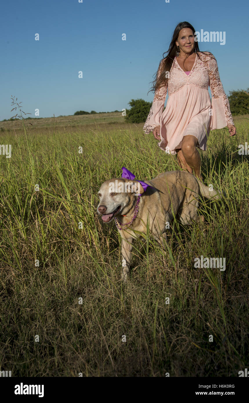 Frau in Oklahoma Spaziergänge ihr Labor Hund im Feld Stockfoto