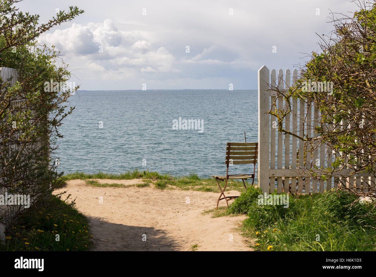 Meerblick vom Strand in Dänemark. Entspannender Blick mit einladenden Stuhl durch den weißen Zaun. Stockfoto