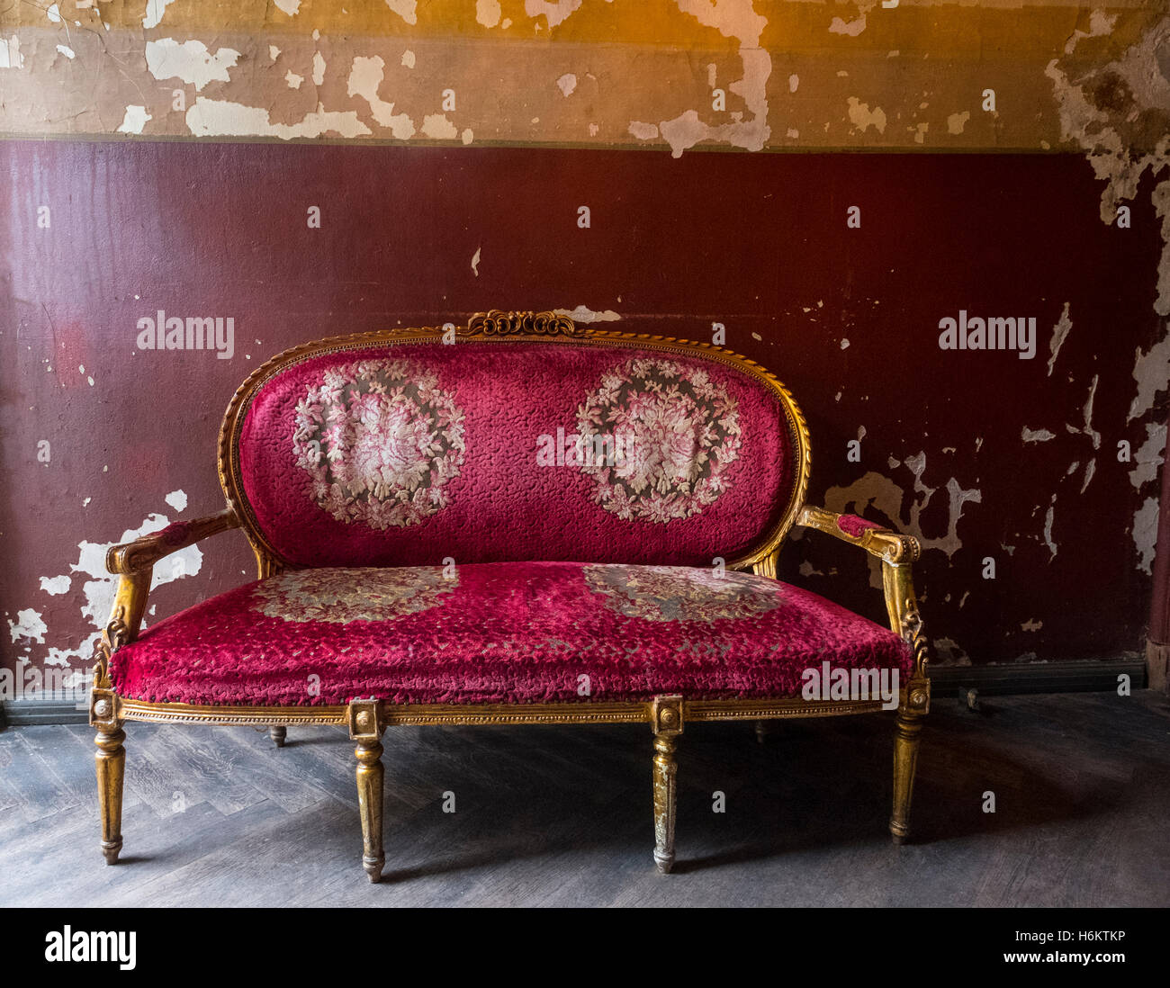Alte antike rotes Sofa mit Gold vergoldet Beine und kunstvolle Dekoration Stockfoto