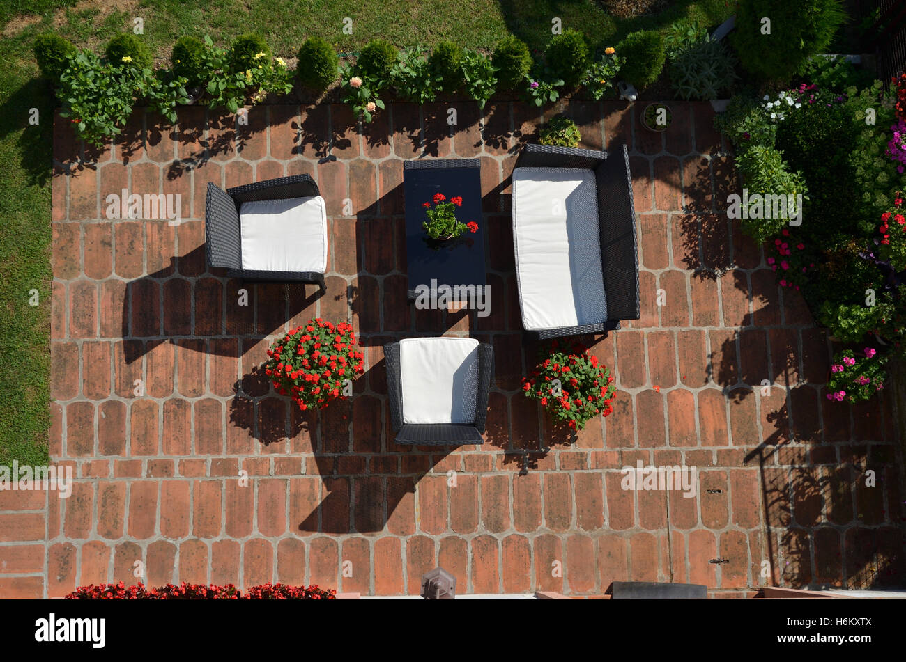 Vogelperspektive von Gartenmöbeln umgeben von Blumen und Pflanzen im Garten Stockfoto