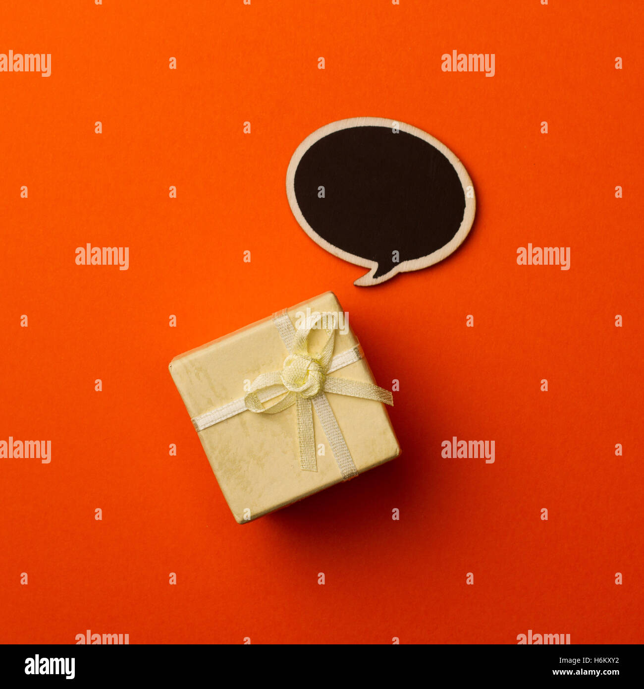Draufsicht der kleinen Geschenkbox auf orangem Hintergrund mit hölzernen schwarze Kreide Board Sprechblase für text Stockfoto