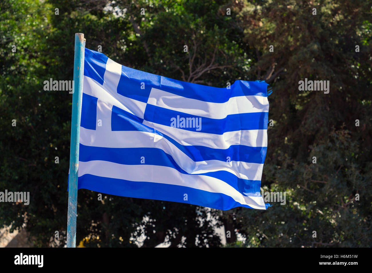 Griechische Flagge flattern im Wind mit dunkelgrünen Hintergrund Stockfoto