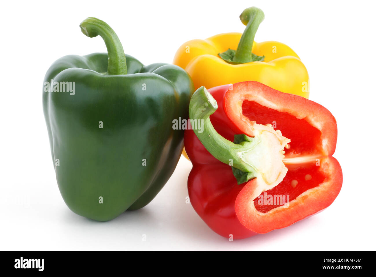 Rote, gelbe und grüne Paprika auf weißem Hintergrund. Rote Paprika halbieren. Stockfoto