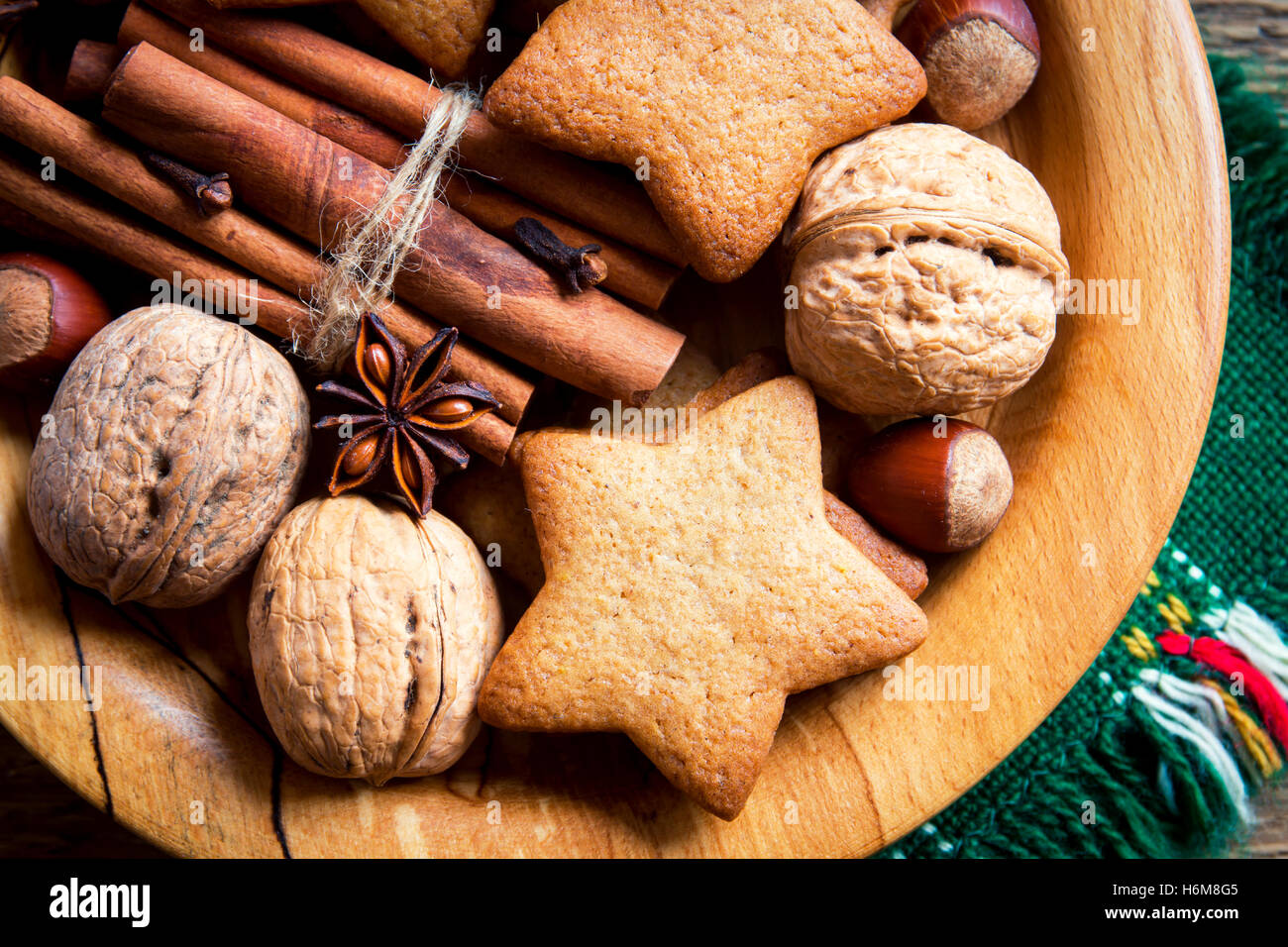 Rustikale Weihnachts-Dekoration mit Lebkuchen, Nüssen und weihnachtlichen Gewürzen über Holzplatte Stockfoto