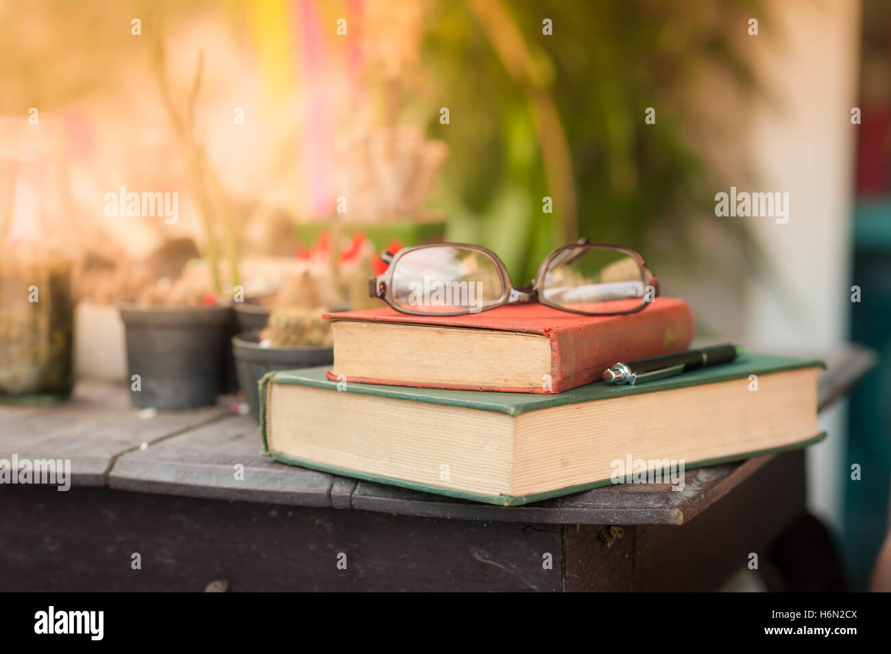 Gläser mit Büchern und Stift auf Holztisch in Morgen Zeit. Wochenende-Lifestyle-Konzept. rote Vintage Buchrücken im Fokus Stockfoto