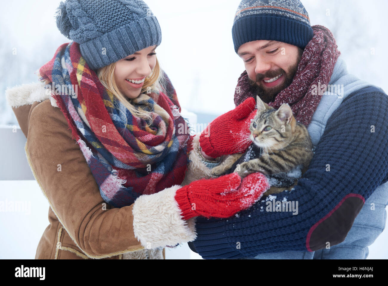 Glückliches Paar mit Katze in Wintertag Stockfoto