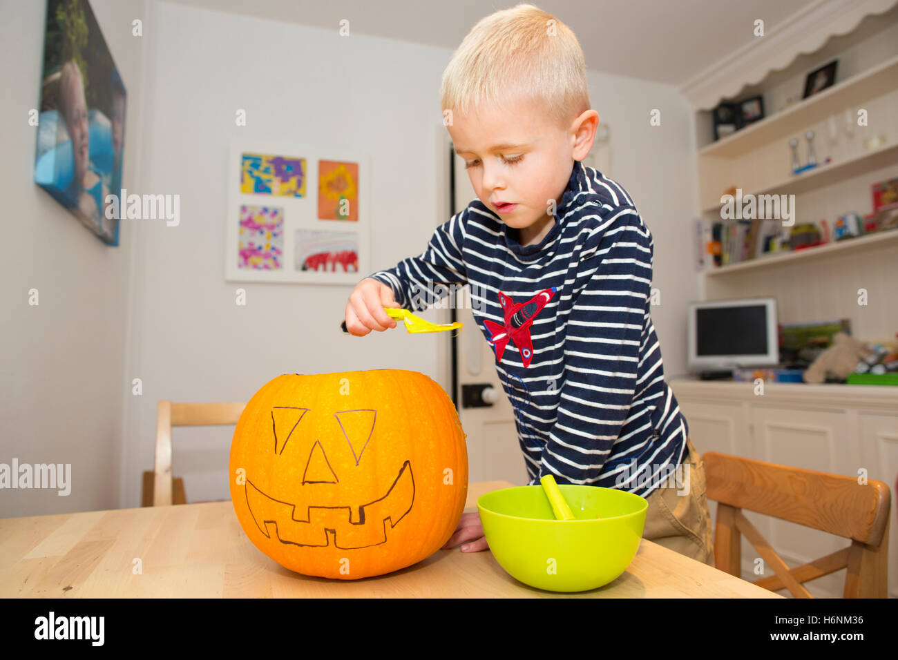 5 Jahre alter Junge aus Kürbis Schaben, wie er seine Jacko-o-Laterne für Halloween-Nacht bereit macht. Stockfoto