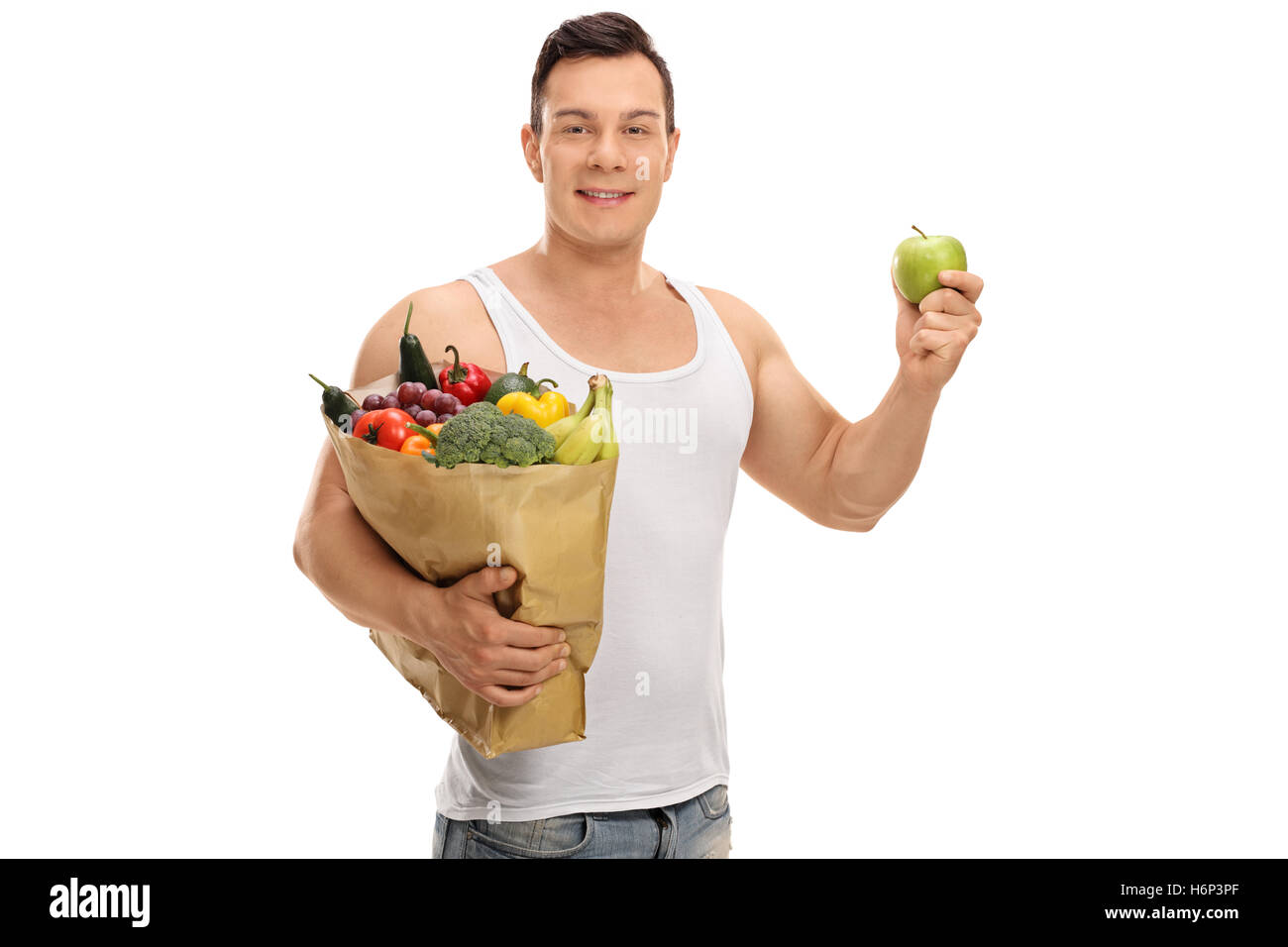Junger Mann hält eine Einkaufstasche voller Obst und Gemüse und ein Apfel isoliert auf weißem Hintergrund Stockfoto