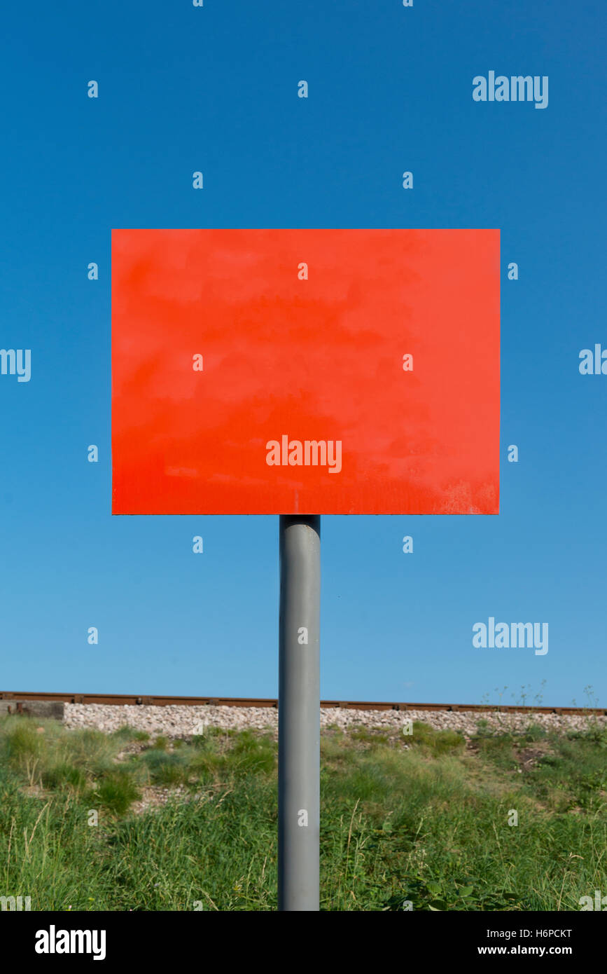 Das zusammengesetzte Bild von leeren roten Schild auf grau Pol mit Bahndamm und Linie im Hintergrund gegen einen klaren blauen Himmel an einem sonnigen Sommer. Stockfoto