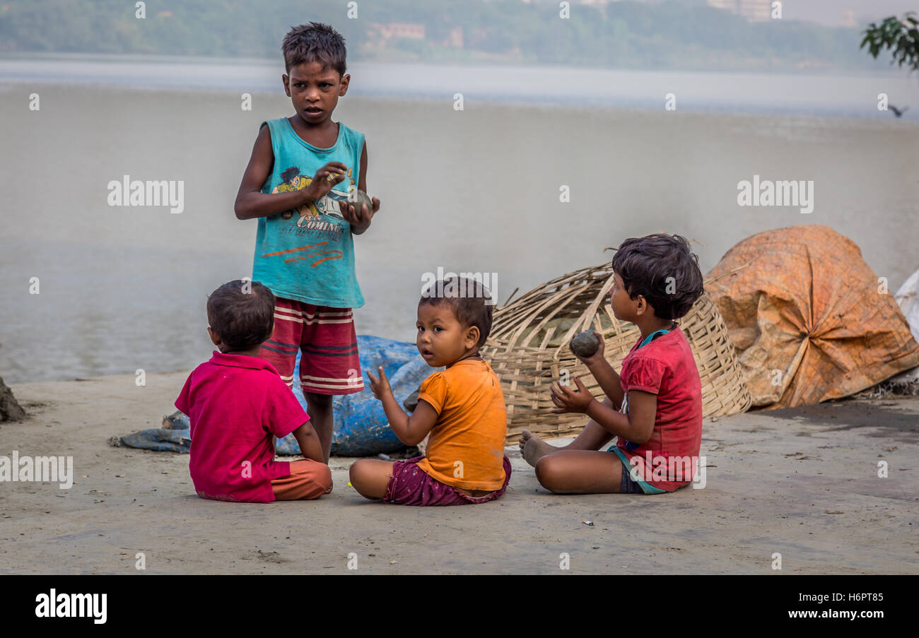 Straßenkinder spielen mit Ton vom Ufer Ganges Flusses auf Mallick Ghat, Blumenmarkt, Kolkata, Indien. Stockfoto