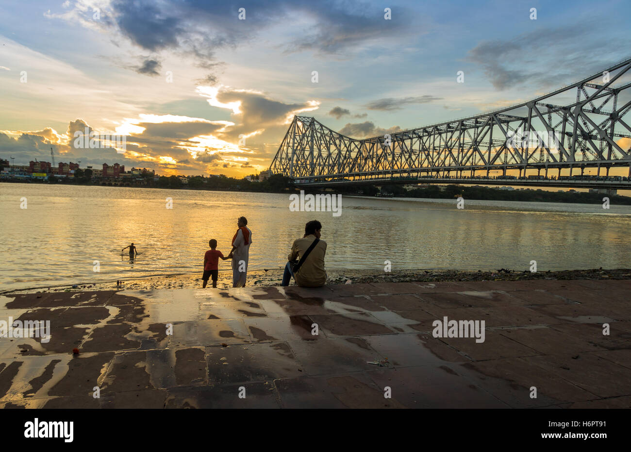 Menschen genießen Sonnenuntergang am Fluss Ganges mit der berühmten Howrah Brücke vor dem Hintergrund. Stockfoto