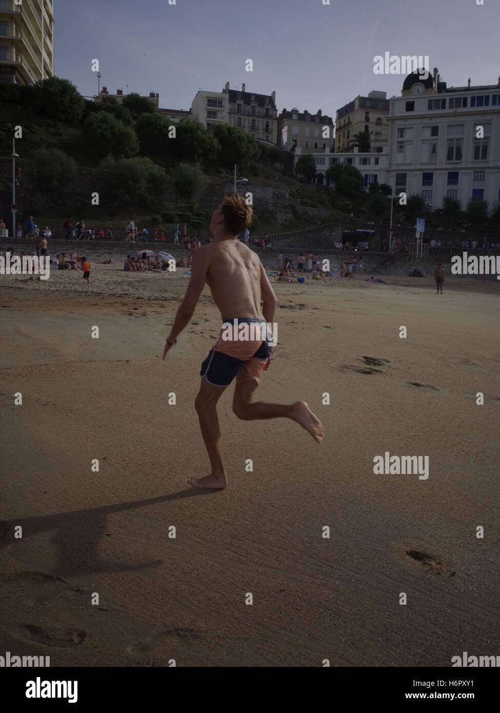 Ein Kumpel läuft nach einer Frisbee am Strand in Biarritz Stockfoto