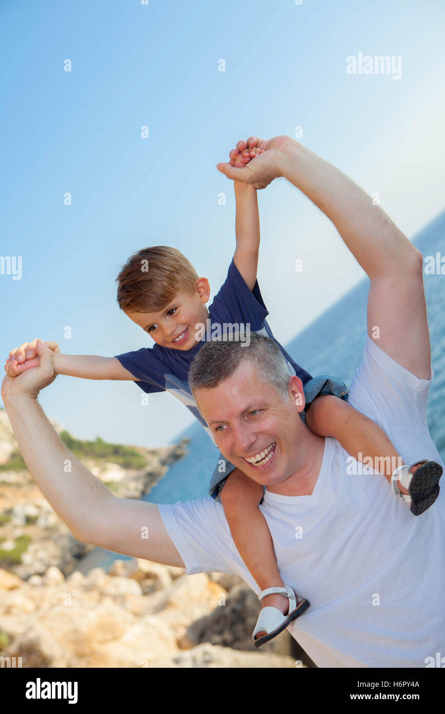 Vater und Sohn Huckepack auf Sommerurlaub Stockfoto