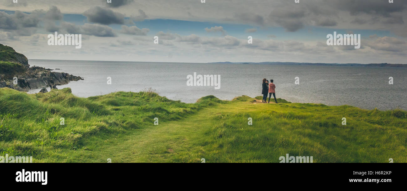 3 Freunde aufpassen über den Ozean in der Nähe der Galley Head Leuchtturm Landzunge an einem schönen sonnigen Herbstmorgen in Irland. Stockfoto