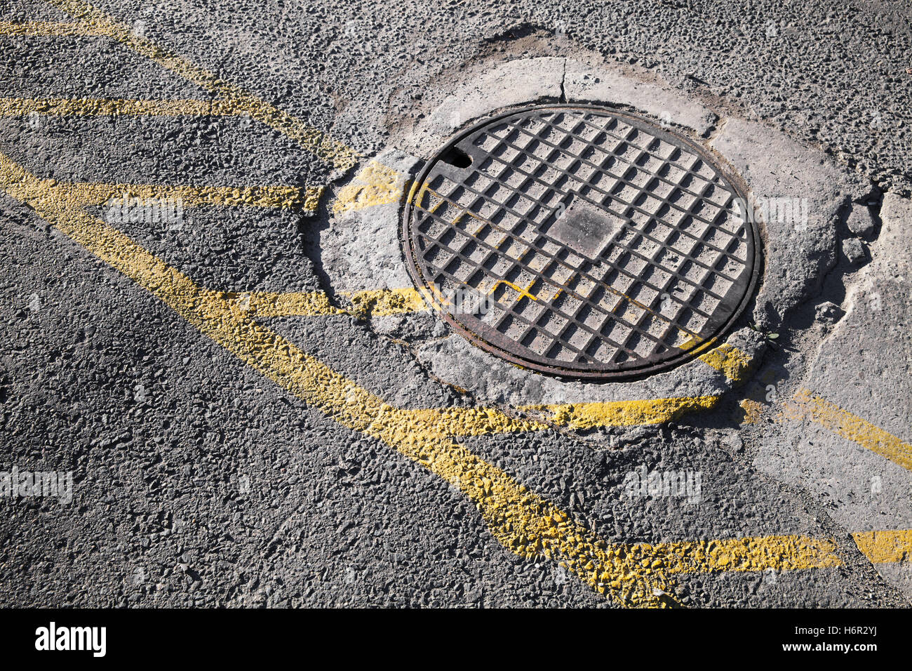 Runde Luke im städtischen Bürgersteig Kanalisation Schacht Abdeckung mit gelbe Straße Markierungslinien Stockfoto