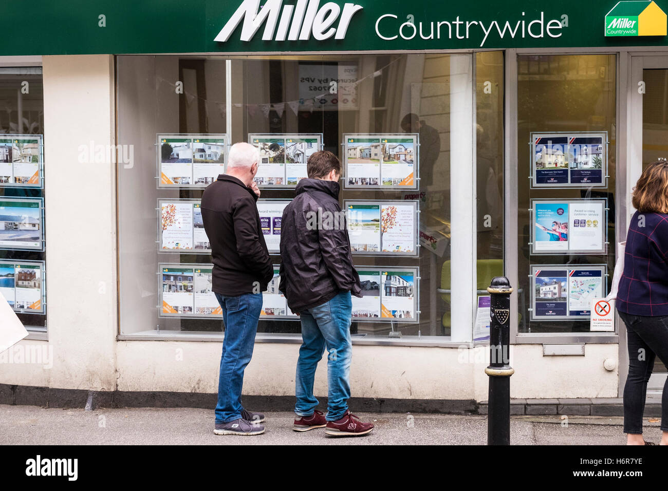 Personen, die Immobilieninformationen in einem Fenster für Immobilienmakler in einem Miller Countrywide Estate Agents in Falmouth, Cornwall, anzeigen. Stockfoto