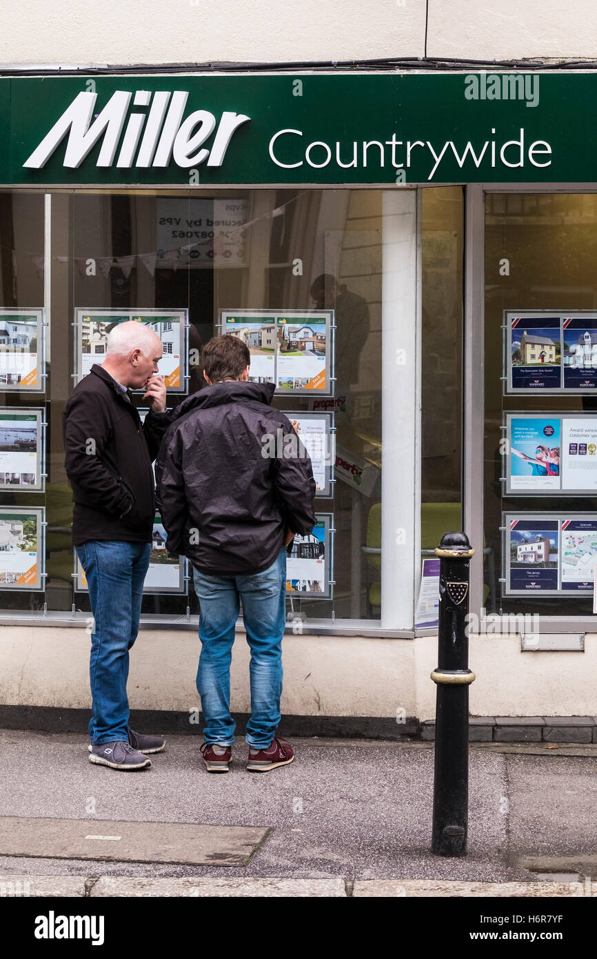 Zwei Personen, die Immobilien in einem Fenster von Miller Countrywide Estate Agents in Falmouth, Cornwall, betrachten. Stockfoto