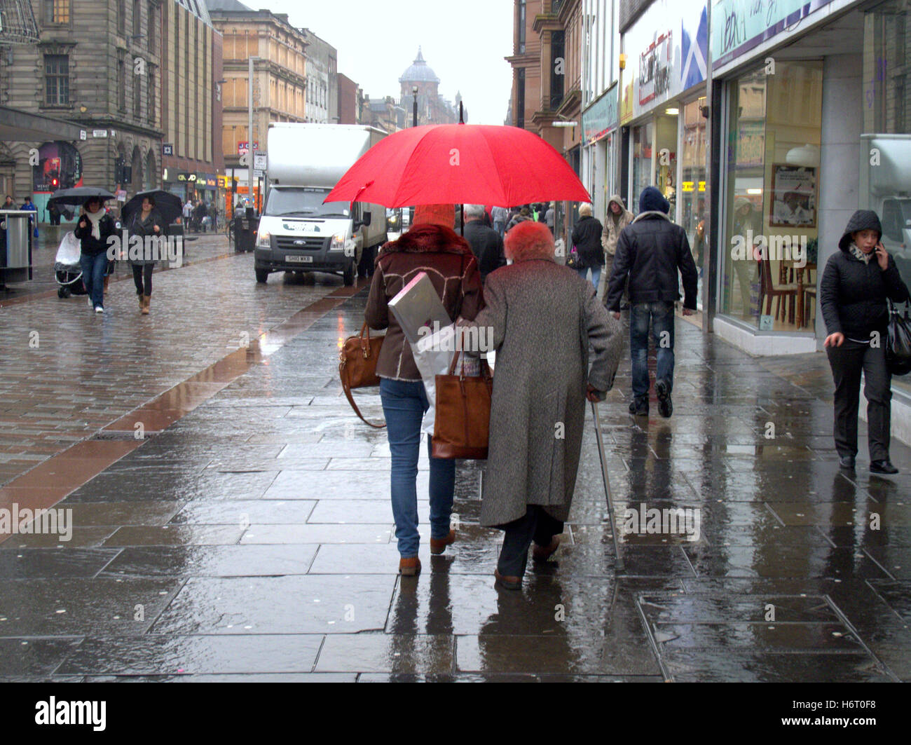 Glasgow in den Regen nassen Straßen und Sonnenschirm Sonnenschirme Einkaufstaschen Stockfoto