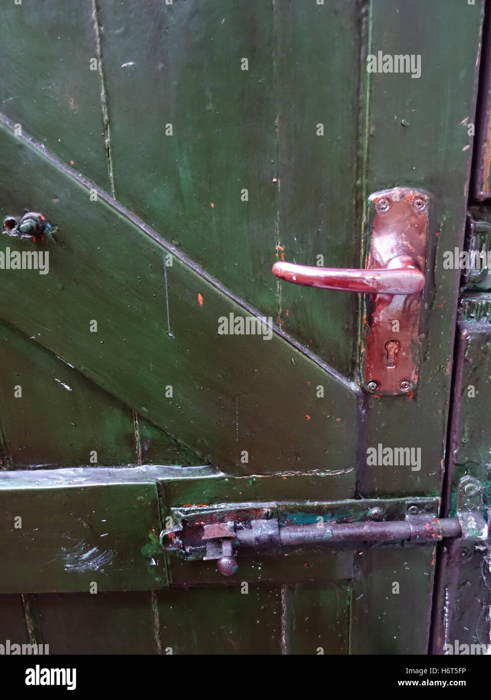 Eine rot angemalt, Metall verarbeiten und Riegel auf einem grünen Holztür. Stockfoto