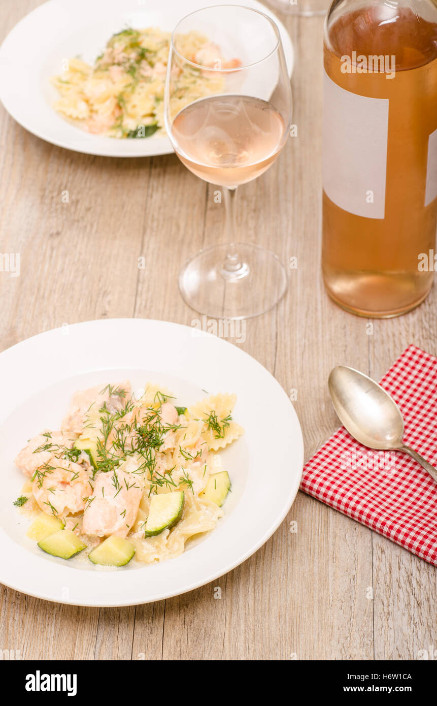 Lachs, Garnelen, Zucchini, Nudeln und ein Glas Wein Stockfoto