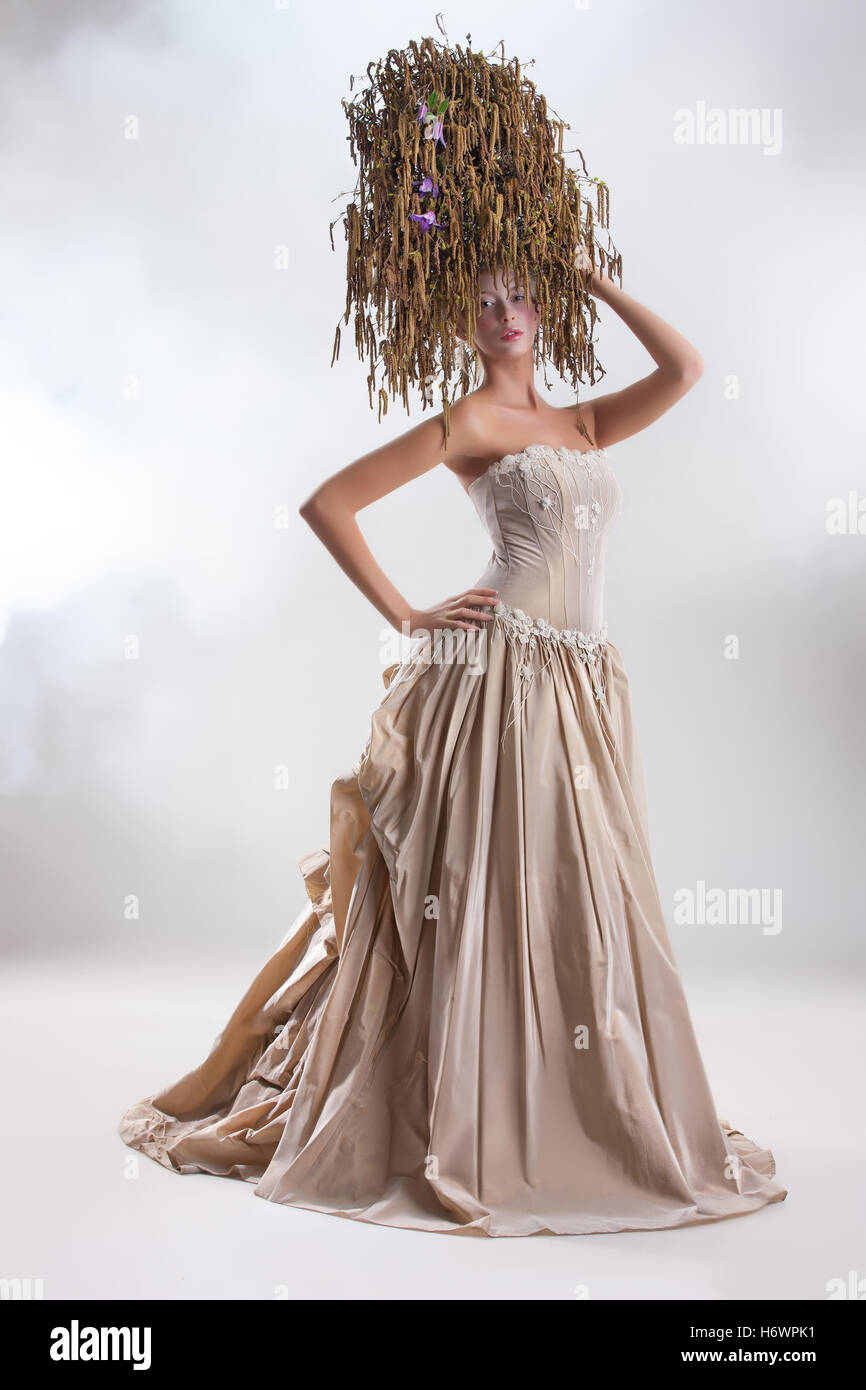 Junge schöne Frau in einem Hochzeitskleid und eine Blume-Komposition auf dem Kopf Stockfoto