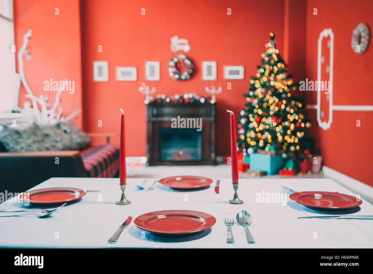 Schön ins neue Jahr Tabelle mit rotem Teller und Besteck auf dem Hintergrund der eingerichtete Zimmer mit Weihnachtsbaum und Kamin gelegt Stockfoto