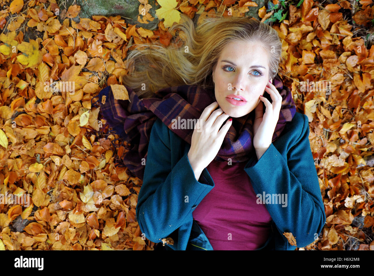 Attraktive Frau, die auf einem Boden von Blättern Stockfoto