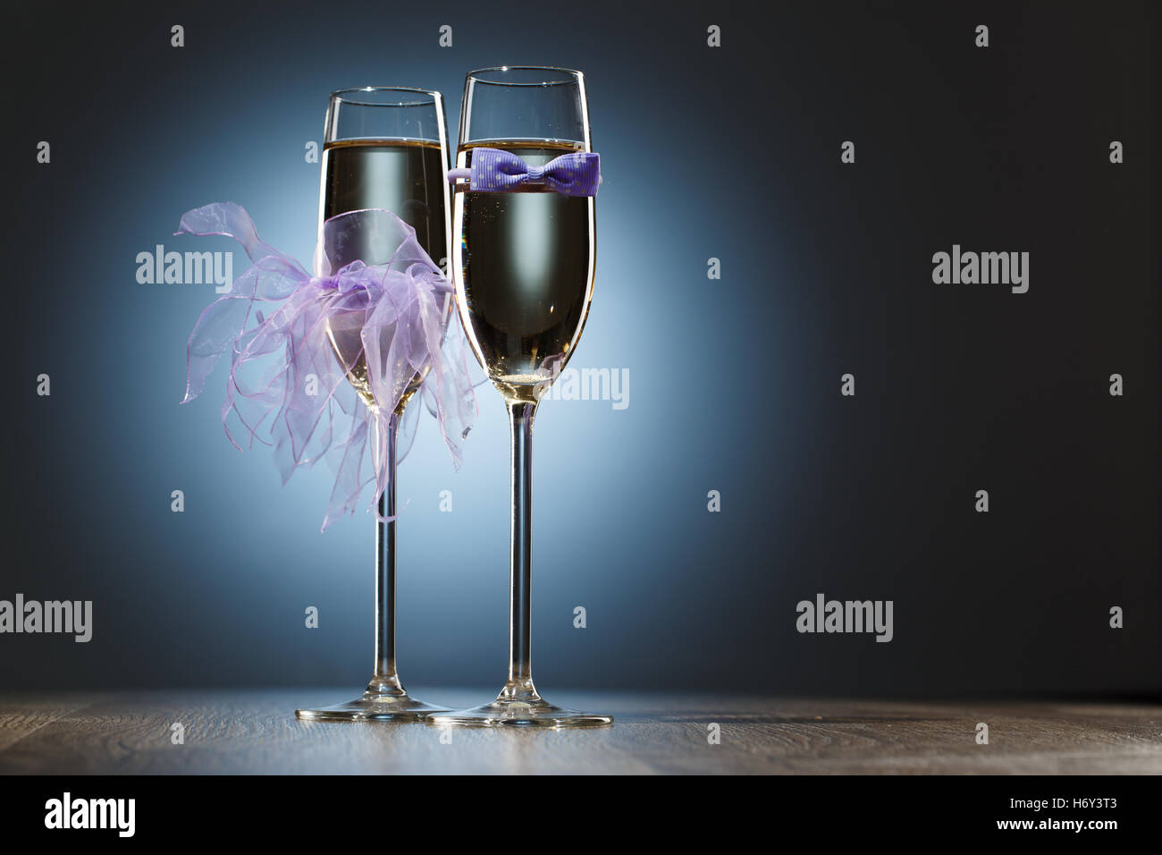 Champagner-Gläser verziert lila Fliege und Schleier für die Flitterwochen. Auf hellen festlichen blauen Hintergrund Stockfoto