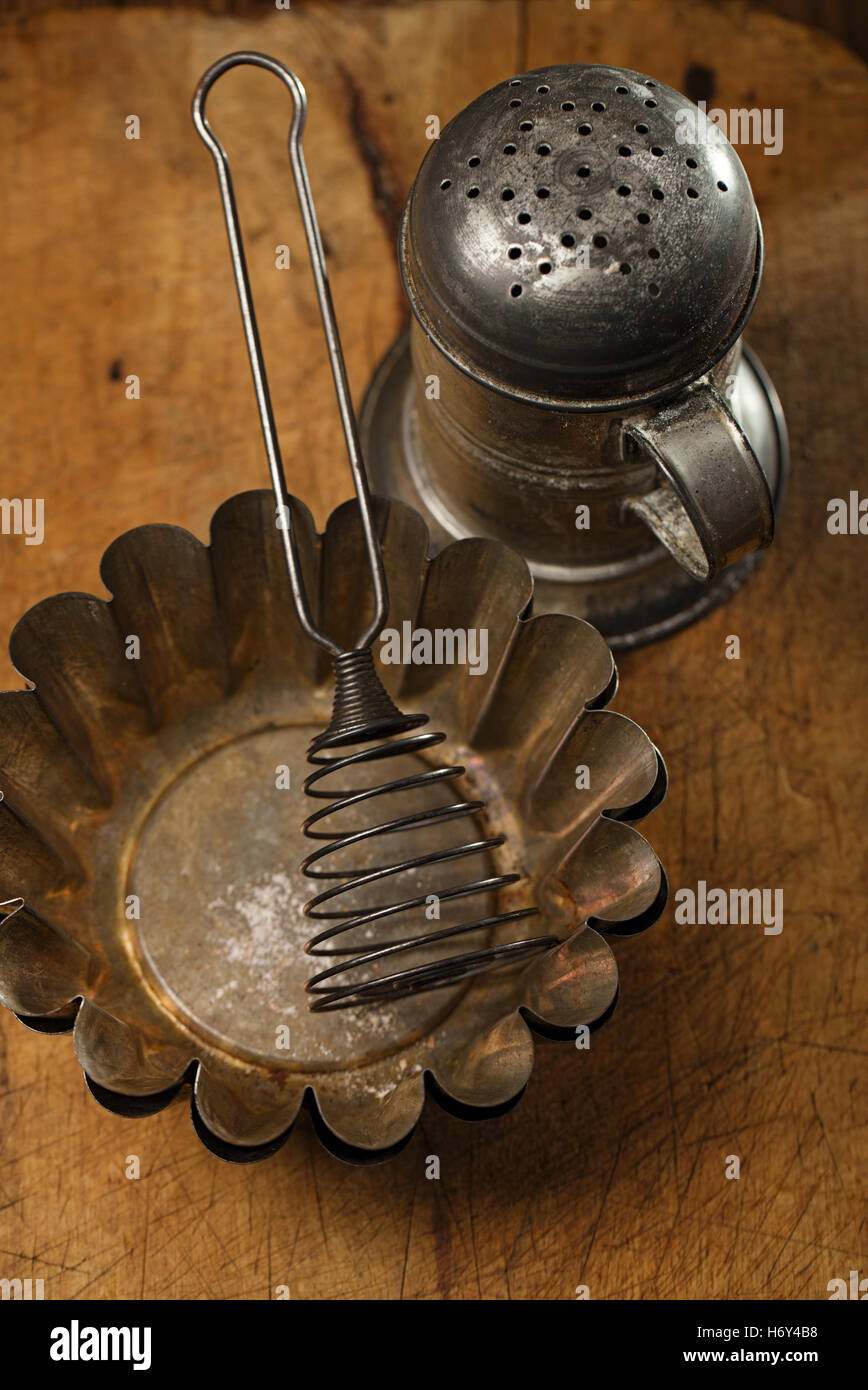 Vintage Backen Geschirr - Sichter, Spachtel, Dosen und Formen auf Holzbrett Stockfoto