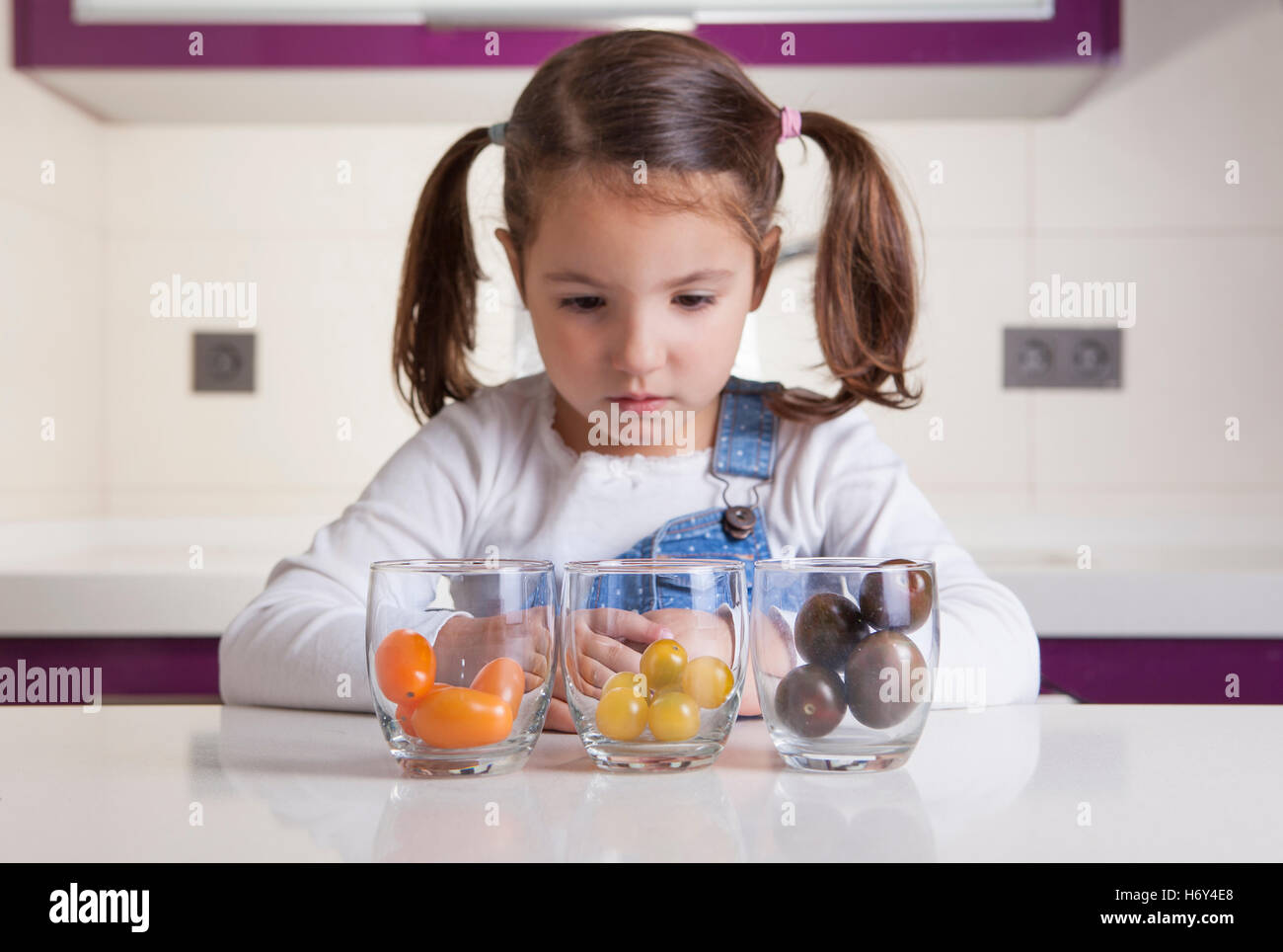 Kleine Mädchen beobachten, Cherry-Tomaten Sorten Farben. Aufklärung über gesunde Ernährung für Kinder Stockfoto