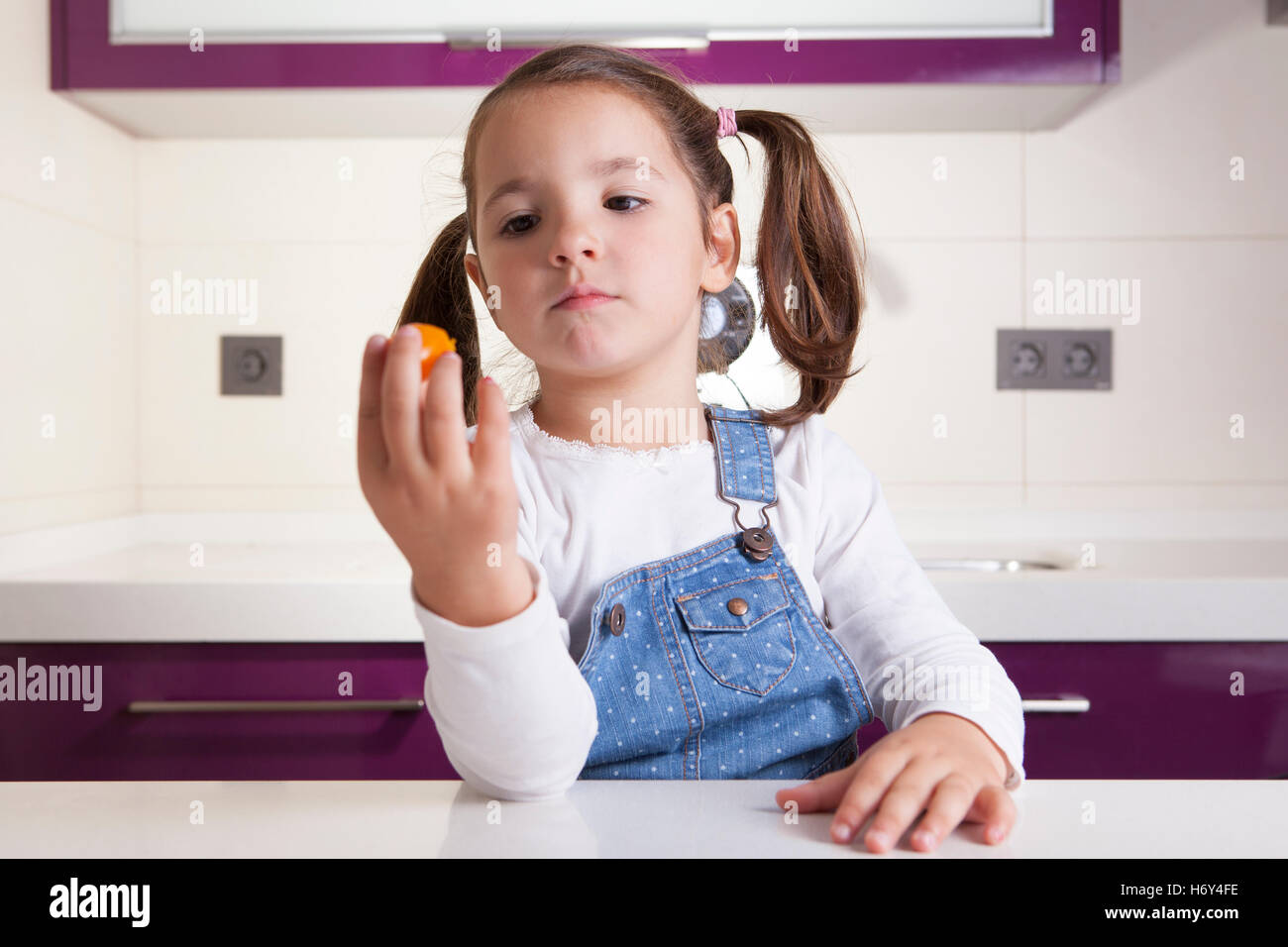 Kleine Mädchen beobachten eine bunte Kirschtomaten vor der Verkostung es Stockfoto