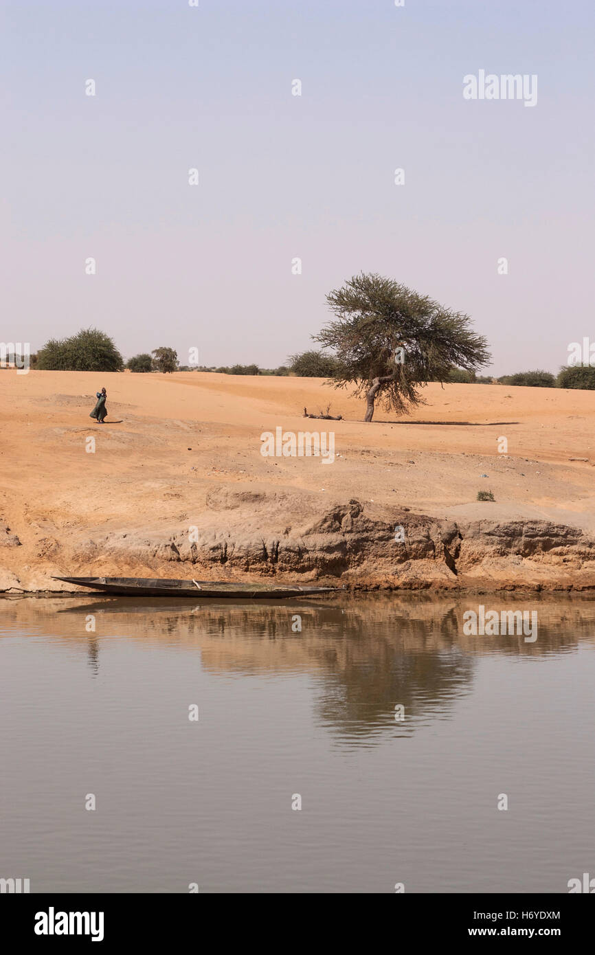 Afrikanerin und Einbaum in einem Landschaft an den Ufern des Flusses Niger in Mali, Afrika Stockfoto