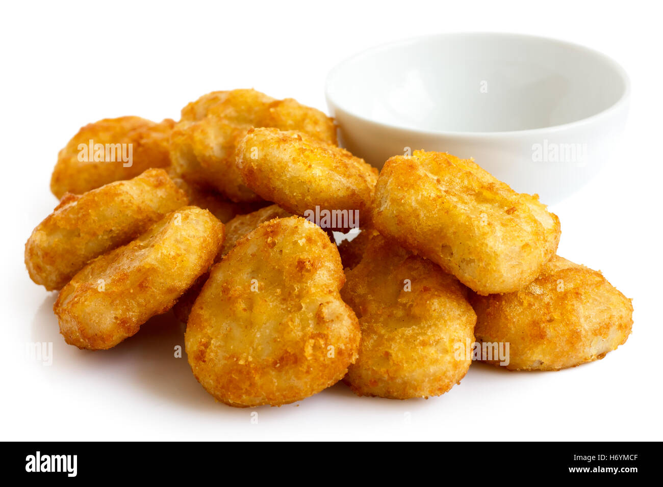 Haufen von golden frittierte angeschlagenen Chicken Nuggets mit leeren Schüssel, isoliert auf weiss. Stockfoto