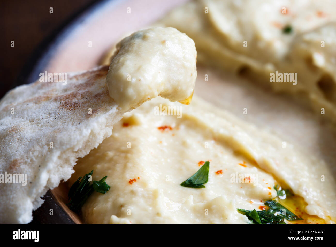 Detail der Hummus auf Pita-Brot. Teller mit gegessen Hummus im Hintergrund. Stockfoto