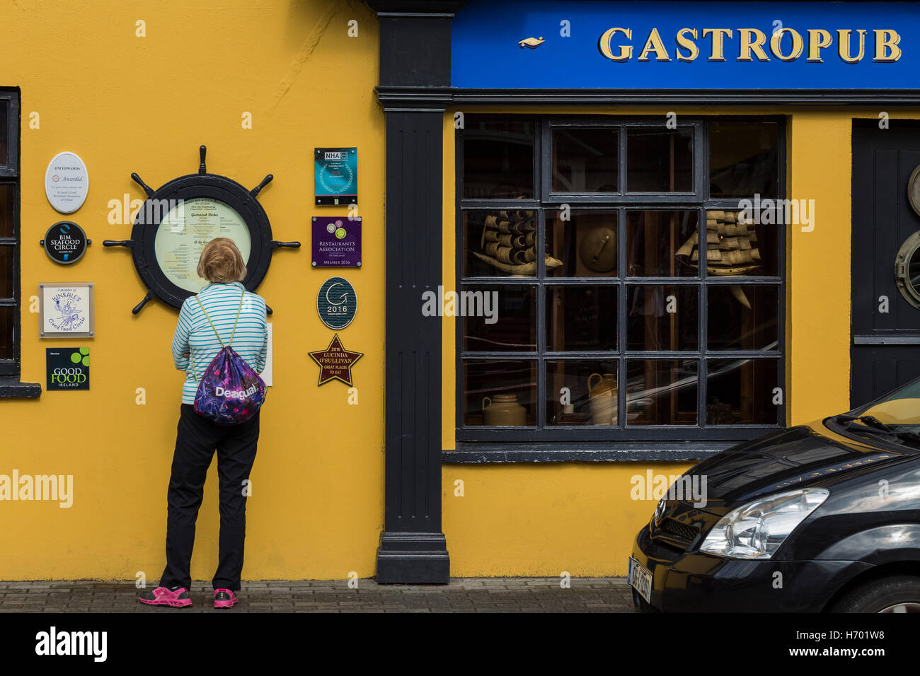 Trendige Frau liest das Menü Outdside Jim Edwards Gastropub in Kinsale, County Cork, Irland Stockfoto